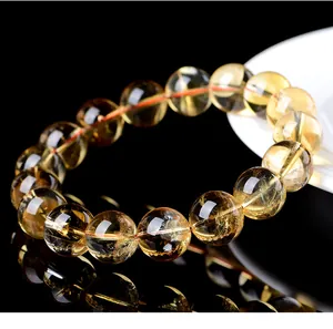 Close-up of natural yellow citrine round bead bracelet on a black reflective background