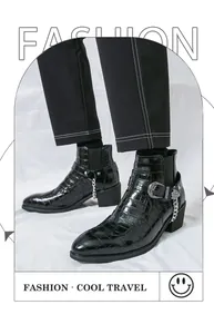 Detail of black crocodile pattern Chelsea boots with silver chain and metal buckle.