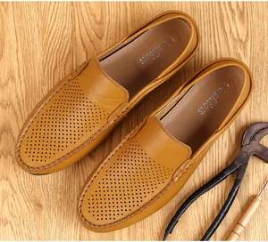 Vista detallada de mocasines de cuero marrón con parte superior perforada en madera.