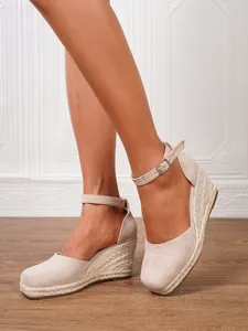 Detalle de sandalias de cuña de alpargata beige con tira al tobillo en pies de modelo