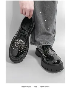 Detail of black glossy leather men's shoes with rivets and white leaf pattern
