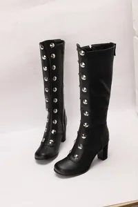 Detailed macro view of black knee-high boots featuring silver studs and chunky heels