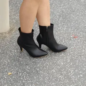 Détail de bottines noires élégantes à bout pointu avec talons hauts et fermeture éclair