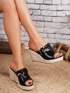 Close-up of stylish black crocodile-embossed espadrille wedge sandals for women