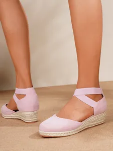 Detalle de sandalias de cuña tipo alpargata rosa con puntera cerrada y tiras elásticas.