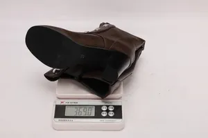 Detailed shot showing the weight of a brown studded chunky heel boot on a scale
