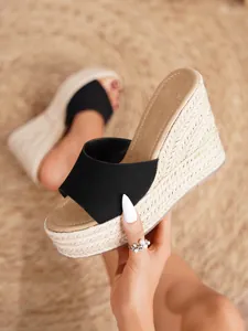 Vista detallada de sandalias de cuña negras con plataforma de paja natural para mujer