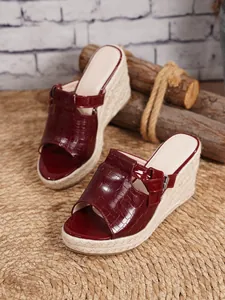 Close-up detail of burgundy crocodile embossed wedge sandals with textured jute platform