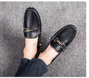Top-down view of black textured leather loafers with golden metal bit detail