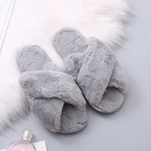 Detailed macro view of soft grey plush criss-cross slippers on a white faux fur rug