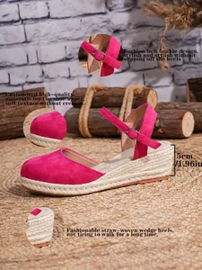 Detalle de sandalias de cuña tipo alpargata fucsia con tacón de paja de 5 cm y correa.