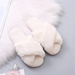 Detail view showing the soft faux fur texture of the cream cross-strap slippers.
