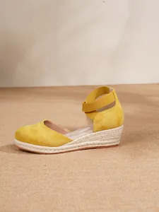 Vista lateral de sandalias de cuña tipo alpargata en ante amarillo con tira elástica