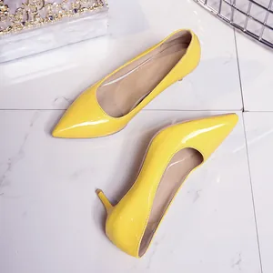Detailed view of elegant yellow patent leather kitten heel pumps with pointed toe.