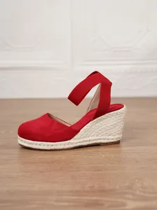 Vista lateral de sandalias de cuña de lona roja para mujer con suela de esparto tejida.