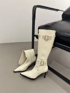 Detail of French vintage cream knee-high boots with silver rivets and buckles