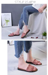 Close-up detail of pink flat slide sandals with ruffled edge design on model's feet