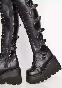 Detail of gothic black over-the-knee wedge boots with buckle straps and platform sole