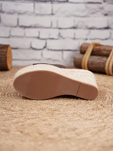 Detalle de cerca de la suela de goma de una sandalia con cuña de esparto trenzado para mujer