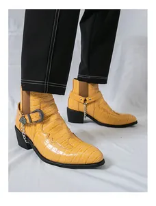 Close-up detail of yellow crocodile embossed men's Chelsea boots with buckle and chain ornament