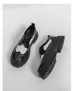 Detailed view of black and white patent leather oxfords with rivets and thick soles.