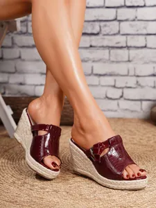 Close-up view of elegant burgundy croc-effect espadrille wedge sandals worn by a model