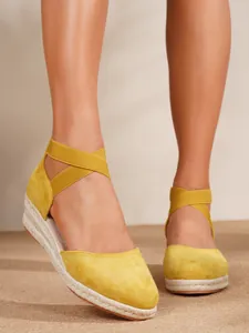Detalle de alpargatas de cuña en ante amarillo con tiras cruzadas al tobillo