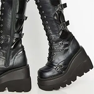 Detail view of black platform wedge boots with multiple metal buckles and laces.