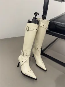 Detailed close-up showing texture of cream white studded knee-high boots with buckles