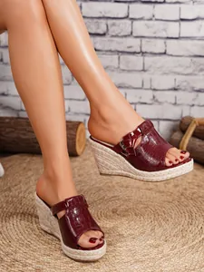 Detail view of women's burgundy crocodile pattern wedge sandals with straw woven platform