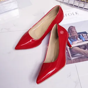 Elegant red patent leather pointed toe high heels displayed on a white marble surface