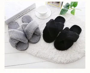 Pair of plush crisscross slippers in grey and black on a cozy white rug detail view
