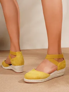 Detalle de sandalias de cuña en ante amarillo con suela de cuerda de yute trenzada