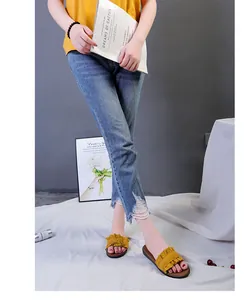 Stylish yellow ruffle flat slide sandals for women worn by a model in casual setting