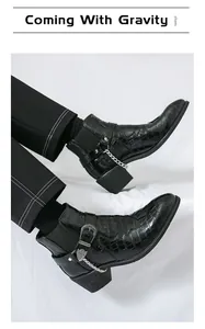 Detailed view of men's black croc-embossed Chelsea boots with chain and buckle details