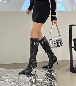 Detail view of black leather knee-high stiletto boots with buckle straps and studs