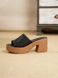 Vista lateral detallada de mule con plataforma de tejido negro y suela de cuña estilo corcho