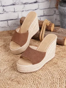 Elegantes sandalias de cuña tipo alpargata de ante marrón con plataforma sobre fondo rústico
