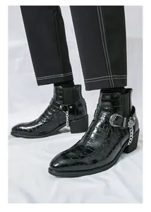 Detailed view of black Chelsea boots with crocodile texture and silver chain buckle.