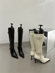 Knee-high stiletto boots in black and off-white with metal stud and buckle details.