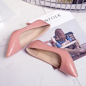 Detailed shot of elegant glossy pink patent leather pointed-toe pumps on marble surface