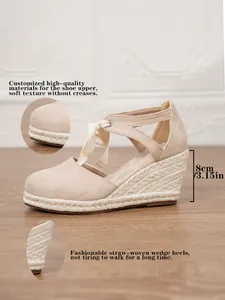 Detalle de sandalias con cuña de paja beige con tacón de 8 cm y parte superior suave.
