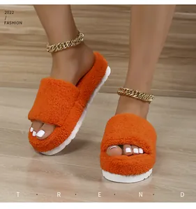 Detail view of vibrant orange fuzzy slippers with chunky white platform soles