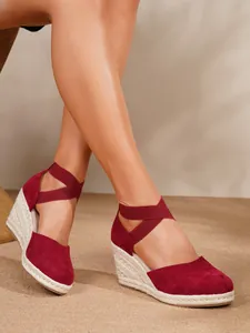 Primer plano de sandalias rojas de cuña de ante con puntera cerrada y suela de cuerda