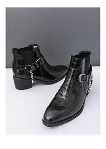 Detail of black crocodile pattern Chelsea boots with silver buckles and chain decoration