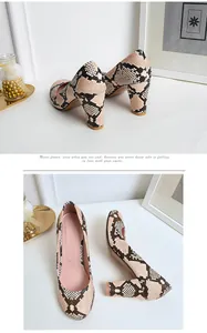 Detail view showing the snakeskin pattern chunky heel pumps on white elegant surface