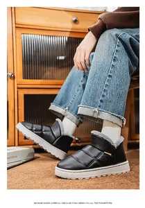 Close-up of men's black quilted slip-on winter boots with fur lining on feet.