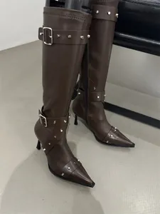 Close-up of brown vintage tall boots with silver studs and pointed toe design