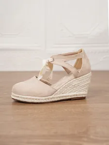 Vista detallada de sandalias de cuña espardeñas beige con cordones de cinta.