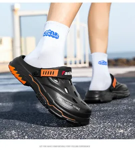 Macro view of black and orange breathable outdoor clogs for men worn on a sunny path